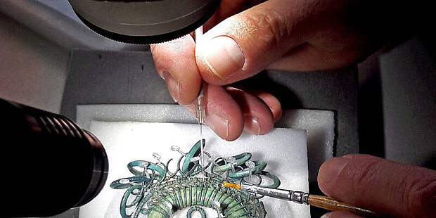 A conservator is working on an object; a close-up view under the microscope